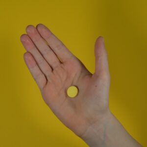 a person holding their hand out with a pill in it