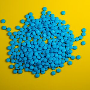 a pile of blue pills on a yellow background