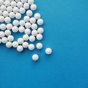 a pile of white pills sitting on top of a blue table