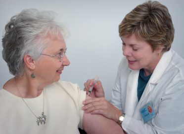 woman inject a woman on left shoulder